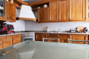 A stylish kitchen with warm wooden cabinets and a contemporary glass table for dining