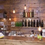 Rustic bar with wooden shelves, wine bottles, and hanging lights.