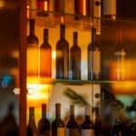 A well-lit glass cabinet displaying a variety of wine and spirit bottles.