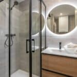A contemporary bathroom interior with a glass-enclosed shower and a stylish sink, highlighting modern design aesthetics.