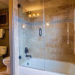 A modern bathroom featuring a glass shower door and a white toilet against neutral-colored walls.