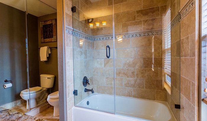 A modern bathroom featuring a glass shower door and a white toilet against neutral-colored walls.