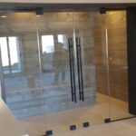 A glass door separates a kitchen from a shower area creating an unusual blend of home spaces