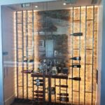 A wine room featuring glass doors and neatly arranged shelves filled with various wine bottles