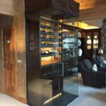 Interior of a wine cellar with a glass door and chairs for guests to relax