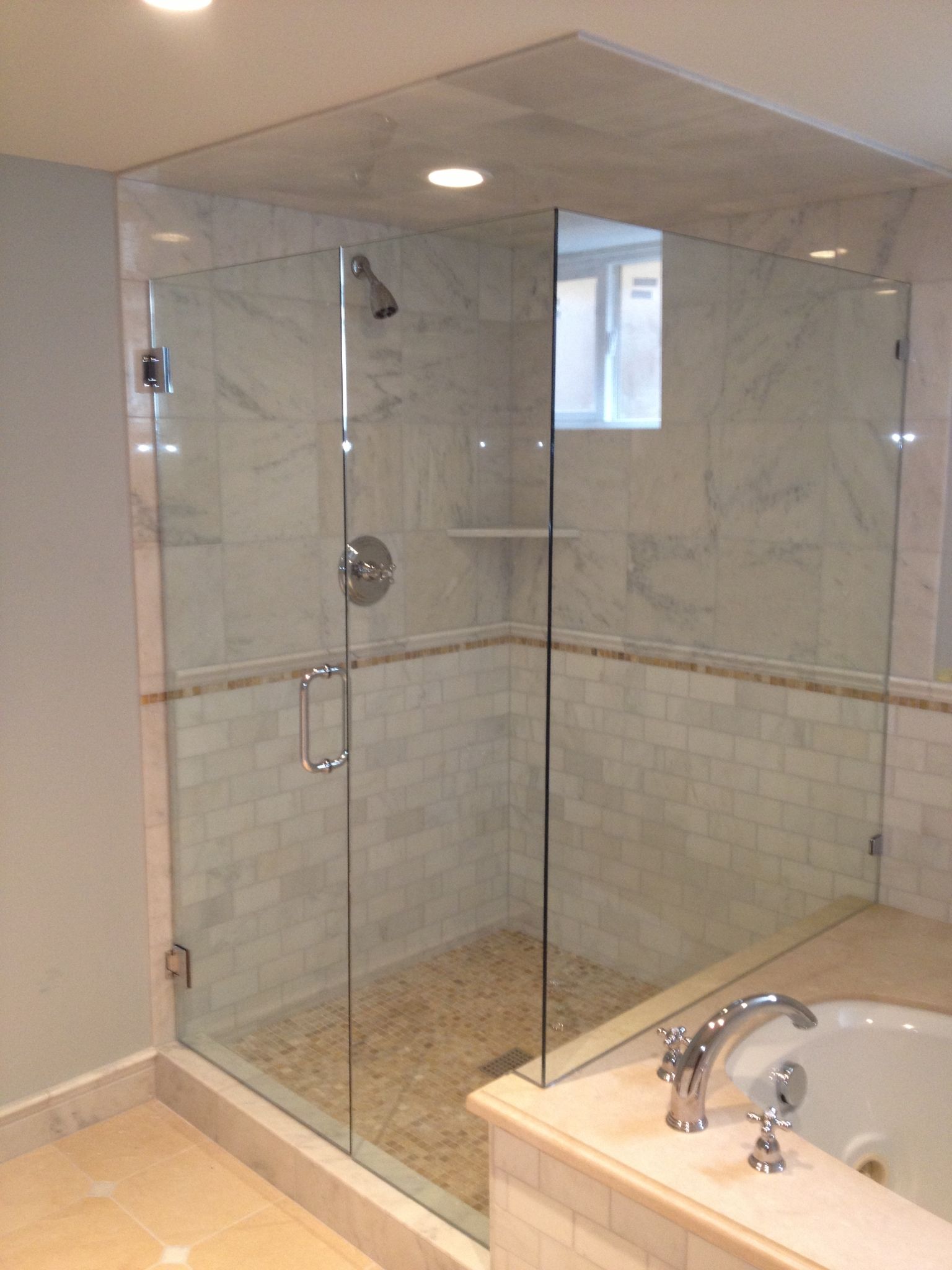 A modern bathroom corner featuring a frameless glass shower enclosure next to a bathtub.